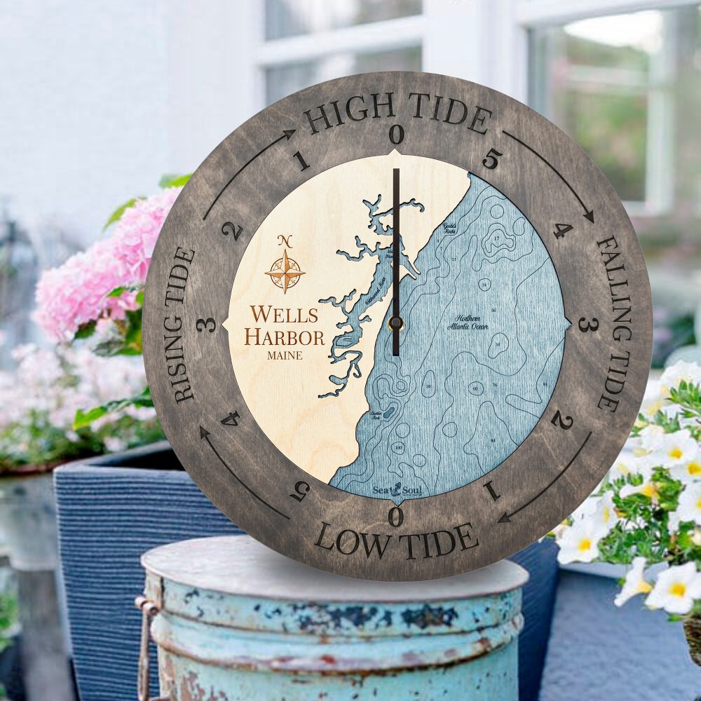 Wells Harbor Tide Clock Driftwood Accent with Blue Green Water Sitting on Bucket Outdoors with Flowers