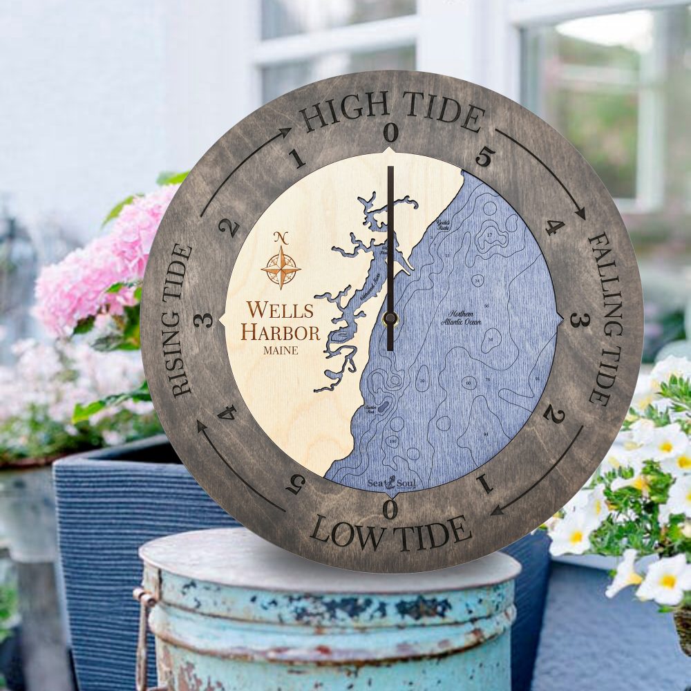 Wells Harbor Tide Clock Driftwood Accent with Deep Blue Water Sitting on Bucket Outdoors with Flowers