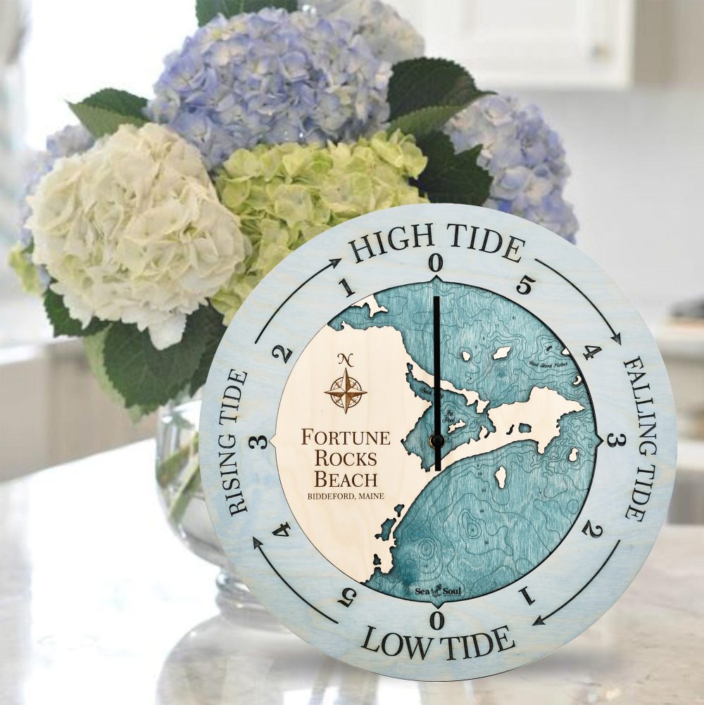Fortune Rocks Beach Tide Clock Bleach Blue Accent with Blue Green Water Sitting on Countertop with Flowers