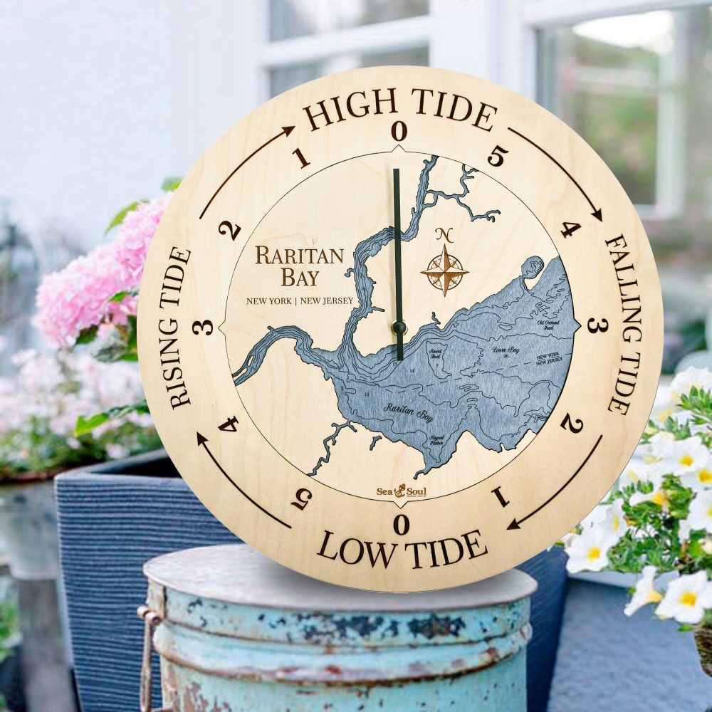 Raritan Bay Tide Clock Birch Accent with Deep Blue Water Sitting on Bucket Outdoors by Flowers