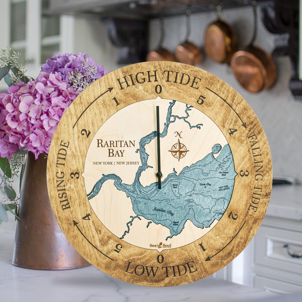 Raritan Bay Tide Clock Honey Accent with Blue Green Water Sitting on Countertop with Flowers