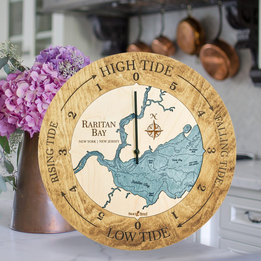 Raritan Bay Tide Clock Honey Accent with Blue Green Water Sitting on Countertop with Flowers