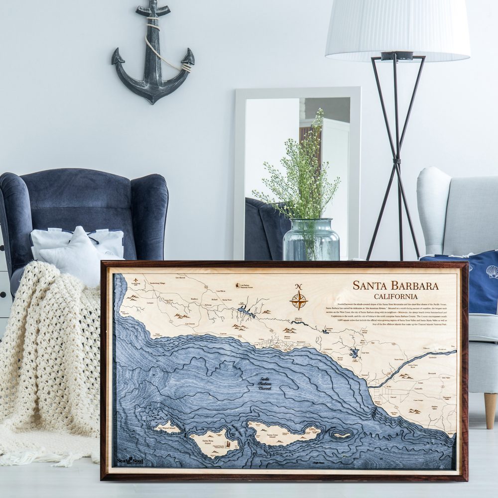 Santa Barbara Nautical Map Wall Art Walnut Accent with Deep Blue Water Sitting on Living Room Floor by Armchair and Coffee Table