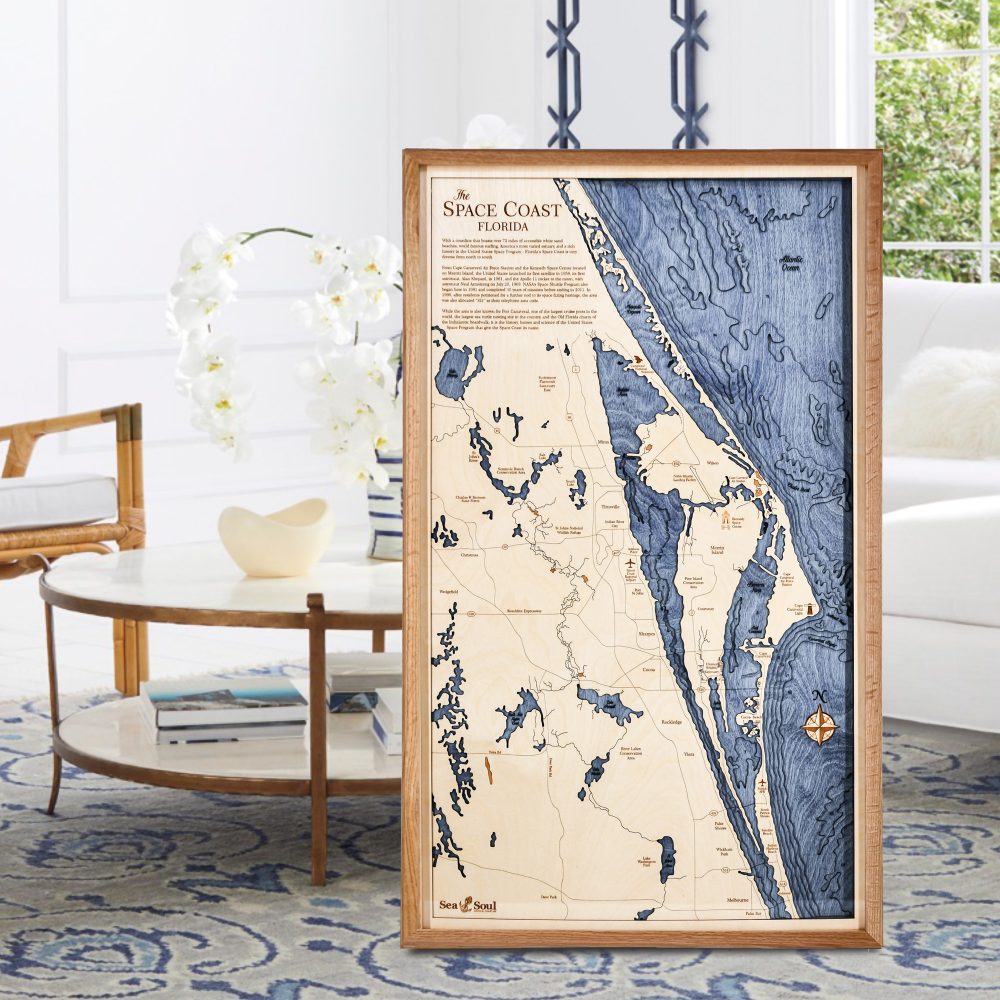 Space Coast Nautical Map Wall Art Cherry Accent with Deep Blue Water Sitting on Living Room Floor by Coffee Table