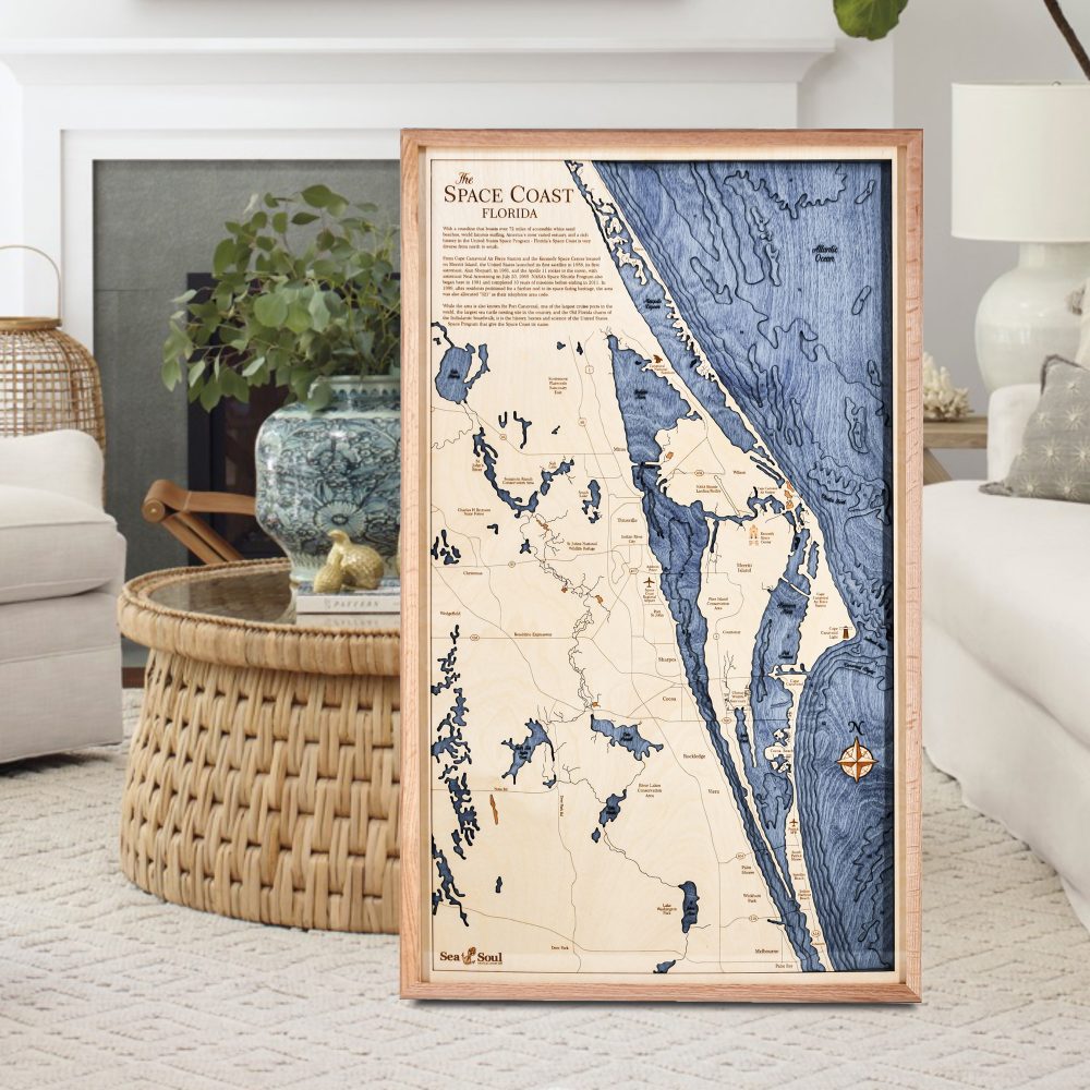 Space Coast Nautical Map Wall Art Oak Accent with Deep Blue Water Sitting on Living Room Floor by Coffee Table