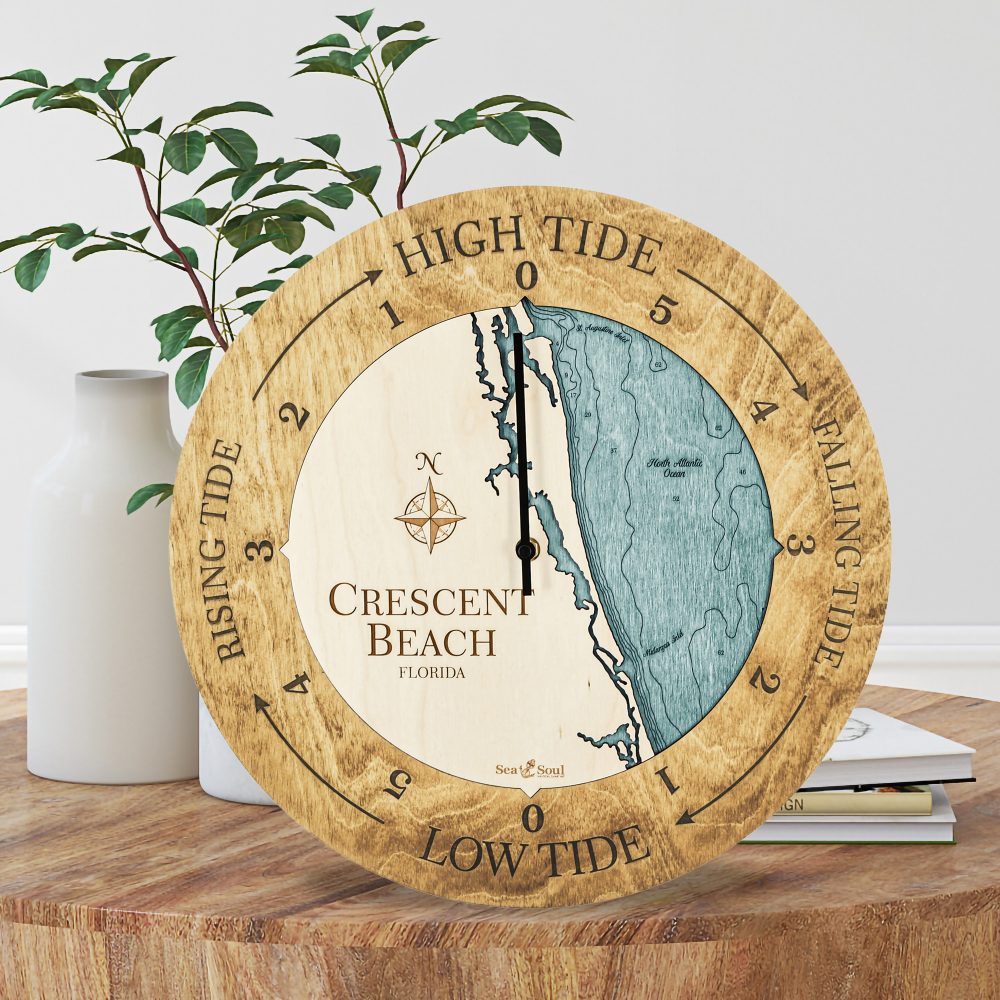 Crescent Beach Tide Clock Honey Accent with Blue Green Water Sitting on Coffee Table by Books and Vases