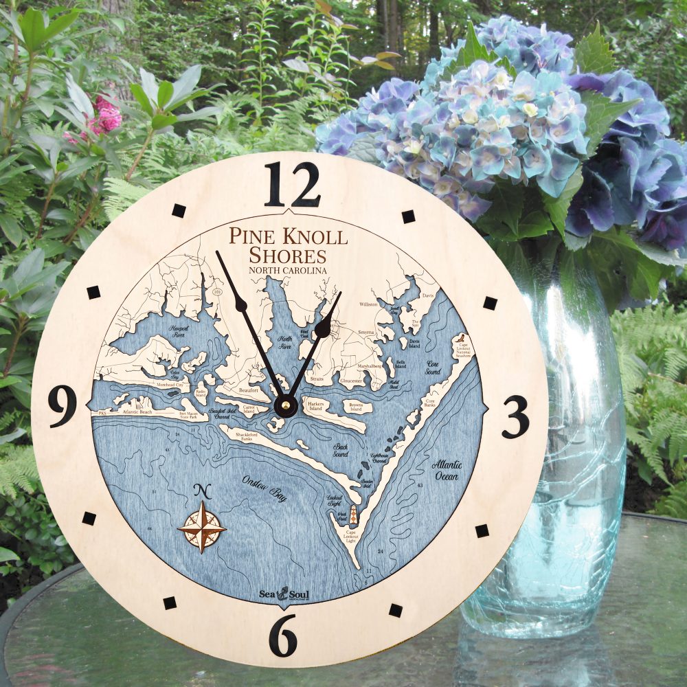 Pine Knoll Shores Nautical Wall Clock Birch Accent with Deep Blue Water Sitting on Outdoor Table by Flowers