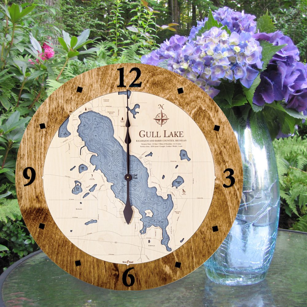 Gull Lake Nautical Clock Americana Accent with Deep Blue Water Sitting on Outdoor Table by Flowers