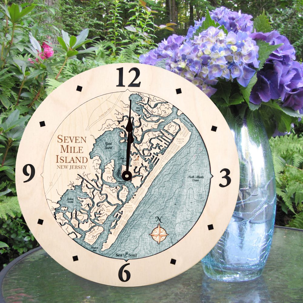 Seven Mile Island Nautical Clock Birch Accent with Blue Green Water Sitting on Outdoor Table by Flowers
