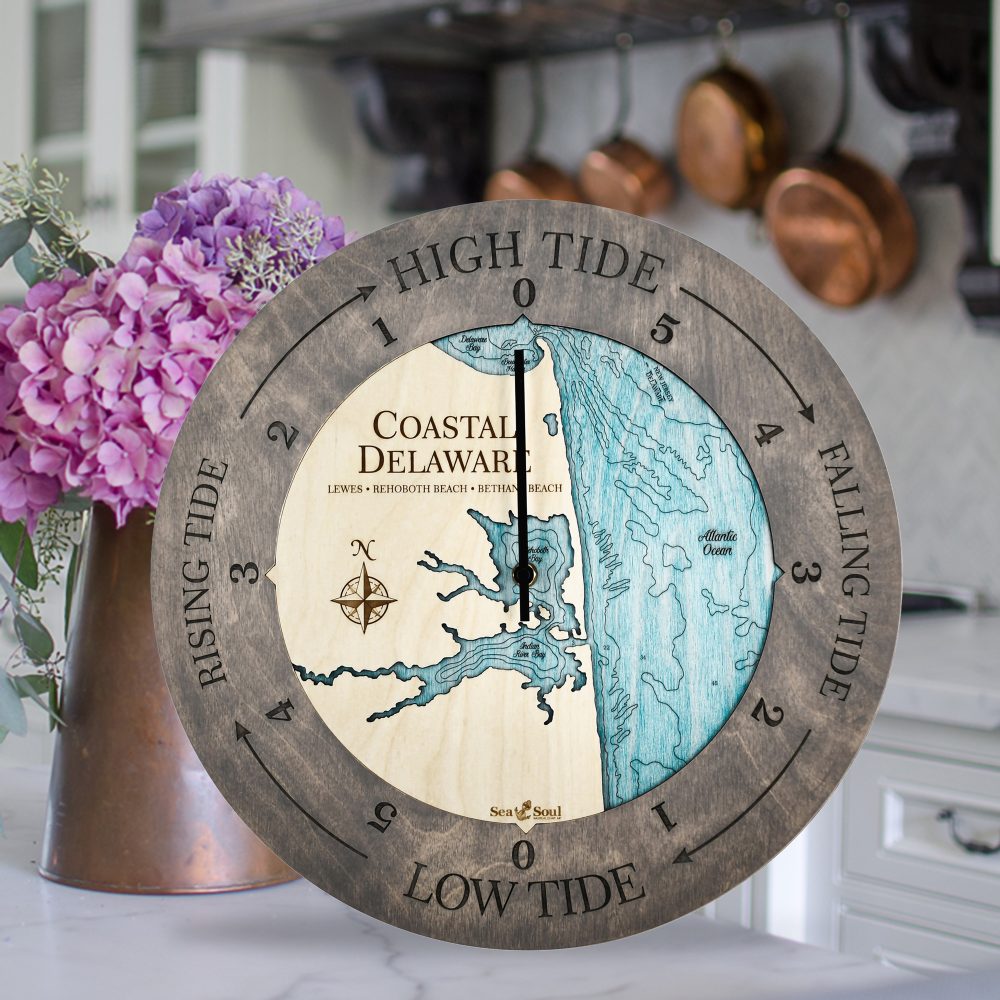 Coastal Delaware Tide Clock Driftwood Accent with Blue Green Water Sitting on Countertop with Purple Flowers