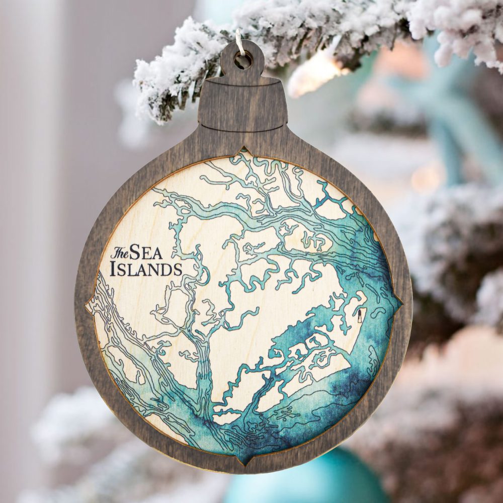 Sea Islands Christmas Ornament Driftwood Accent with Blue Green Water Hanging on Pine Tree Outside with Snow