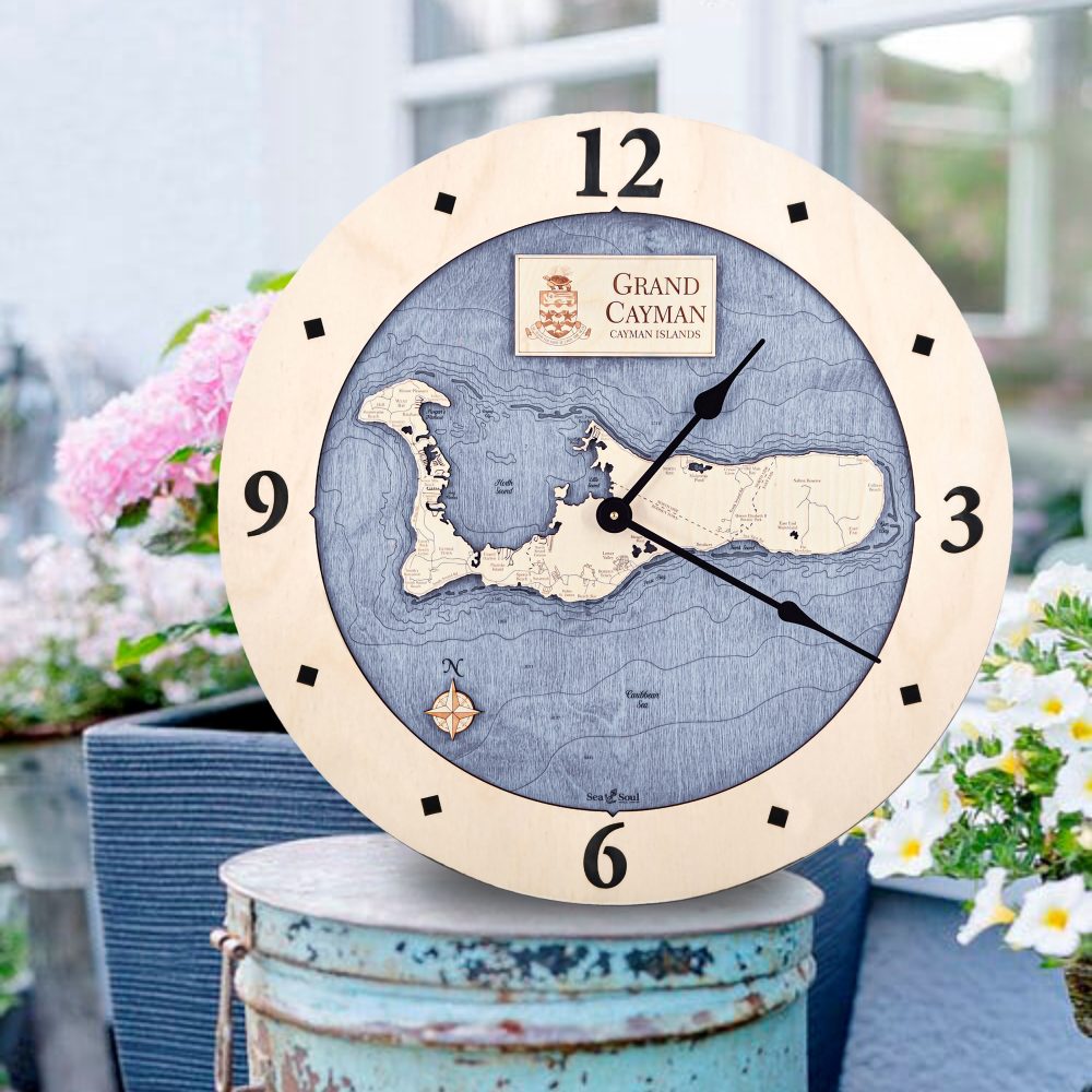 Grand Cayman Nautical Map Clock Birch Accent with Deep Blue Water Sitting on Outdoor Bucket by Flowers