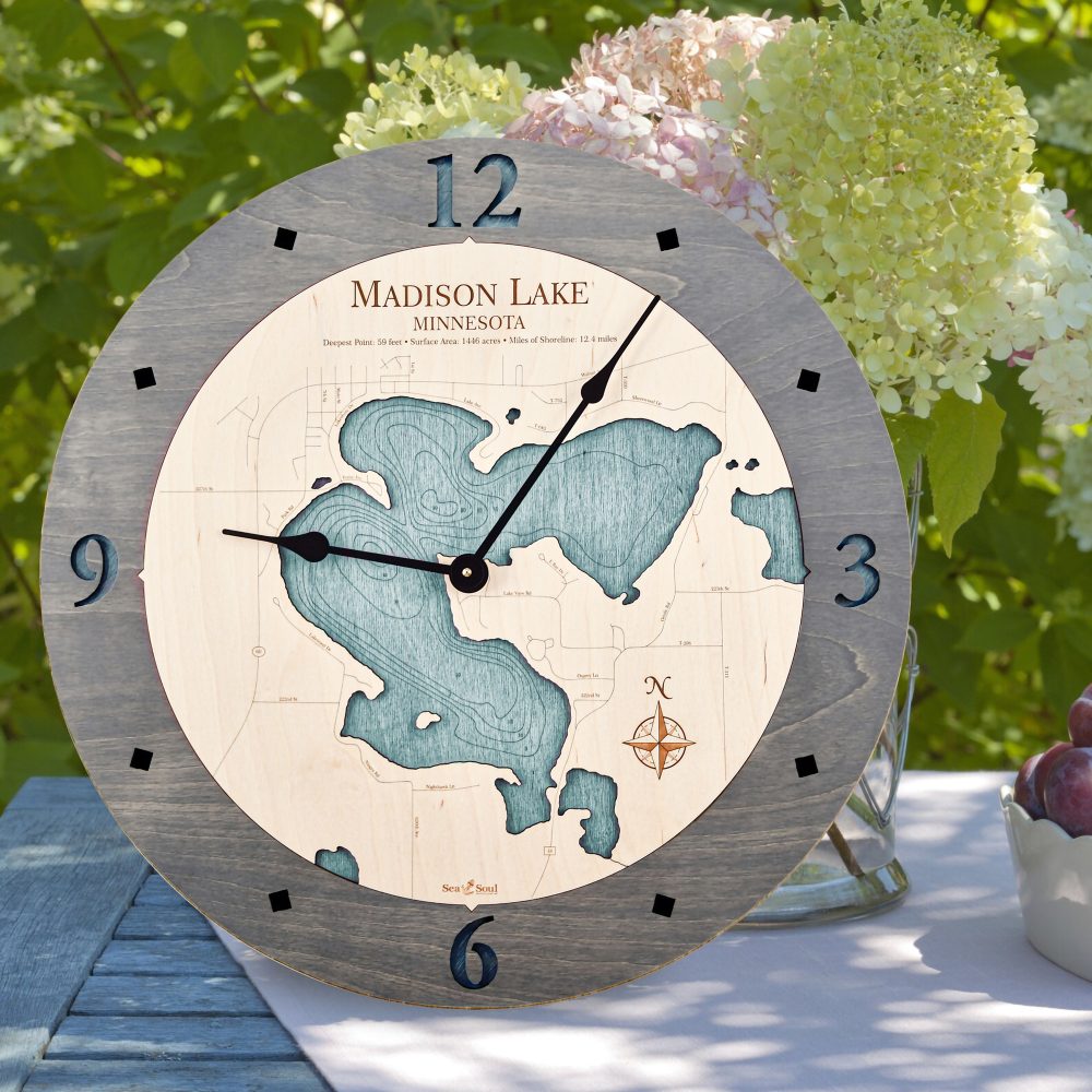 Madison Lake Nautical Map Clock Driftwood Accent with Blue Green Water Sitting on Outdoor Table by Flowers